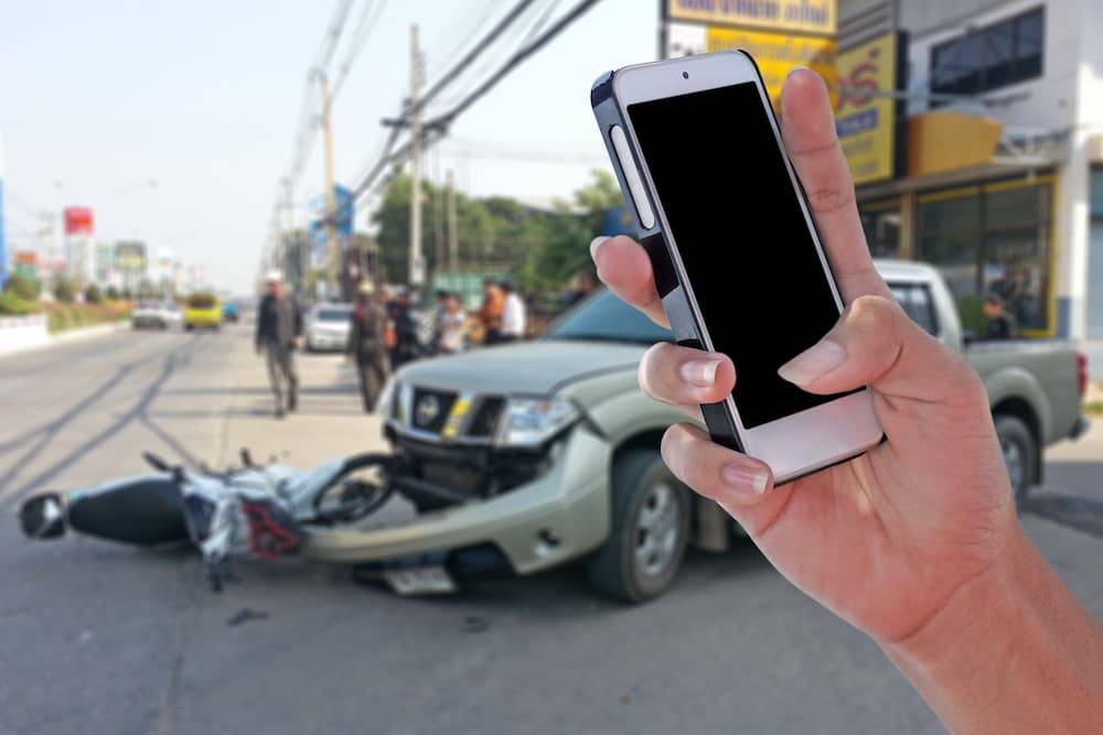 Woman taking an picture of a car crash with her phone
